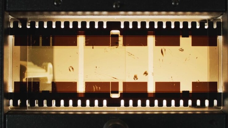 Una pellicola da 35mm che avanza attraverso il gate del proiettore dopo l'ingranamento della ruota dentata, per la proiezione.
