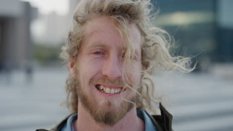 portrait happy young man smiling enjoying relaxed urban lifestyle bearded hipster male wind blowing hair in city at sunset