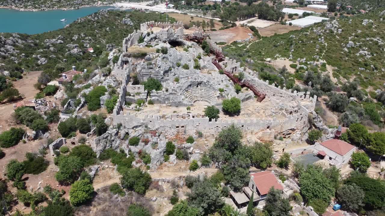 Drone video capturing the impressive hilltop ruins of an ancient amphitheater and fortress near Phaselis, Antalya Province. Rugged rocky landscape and coastal vistas enhance the historic setting