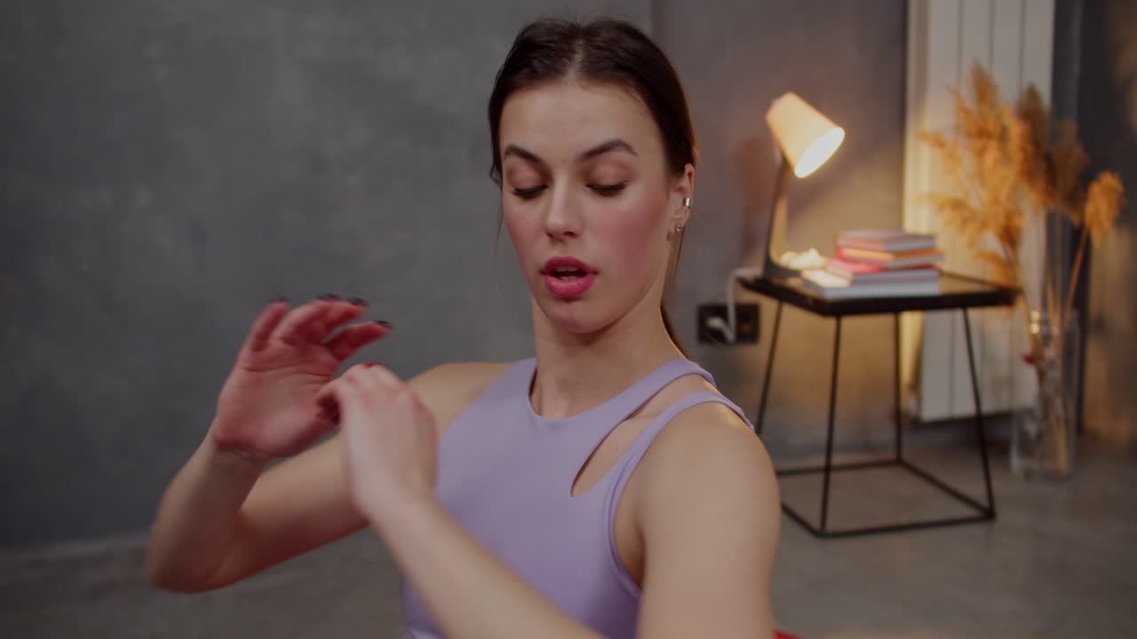 cerca de una chica morena segura con una constitución atlética en una camiseta deportiva púrpura usa una alfombra roja y hace deportes y bombea sus abdominales en un apartamento moderno en casa