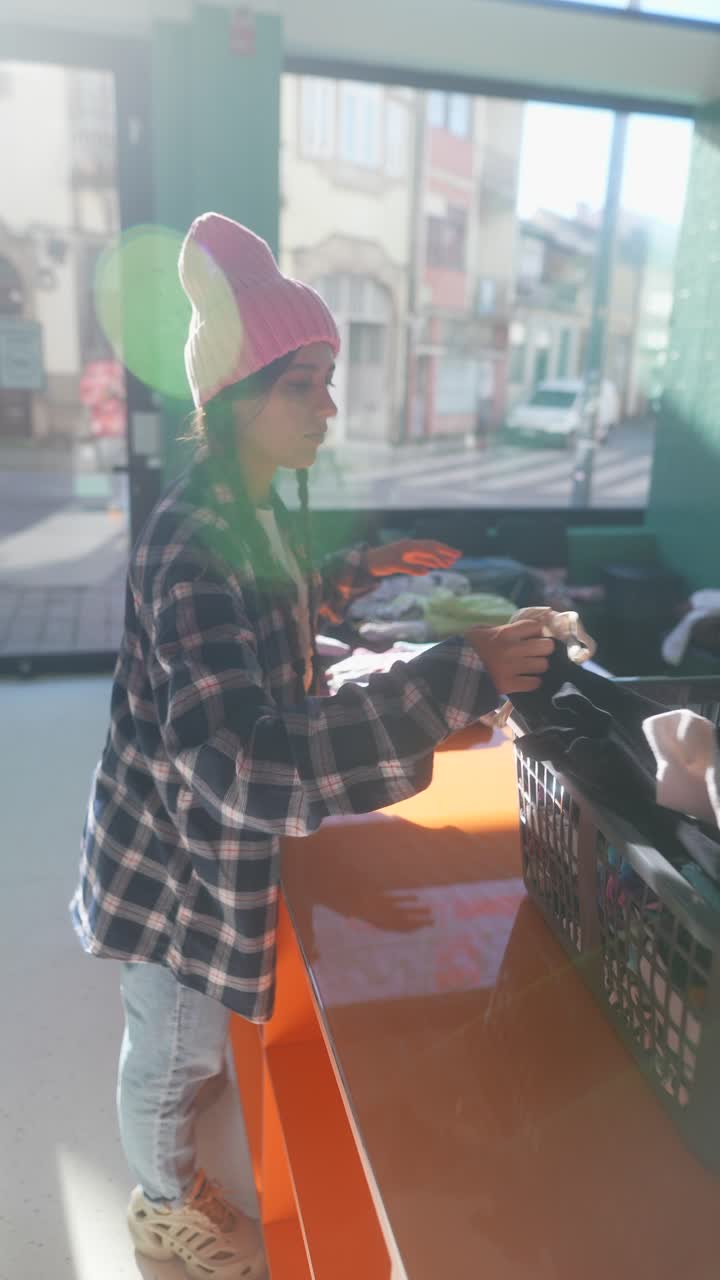 una joven que se ofrece como voluntaria en un centro de donación de ropa.