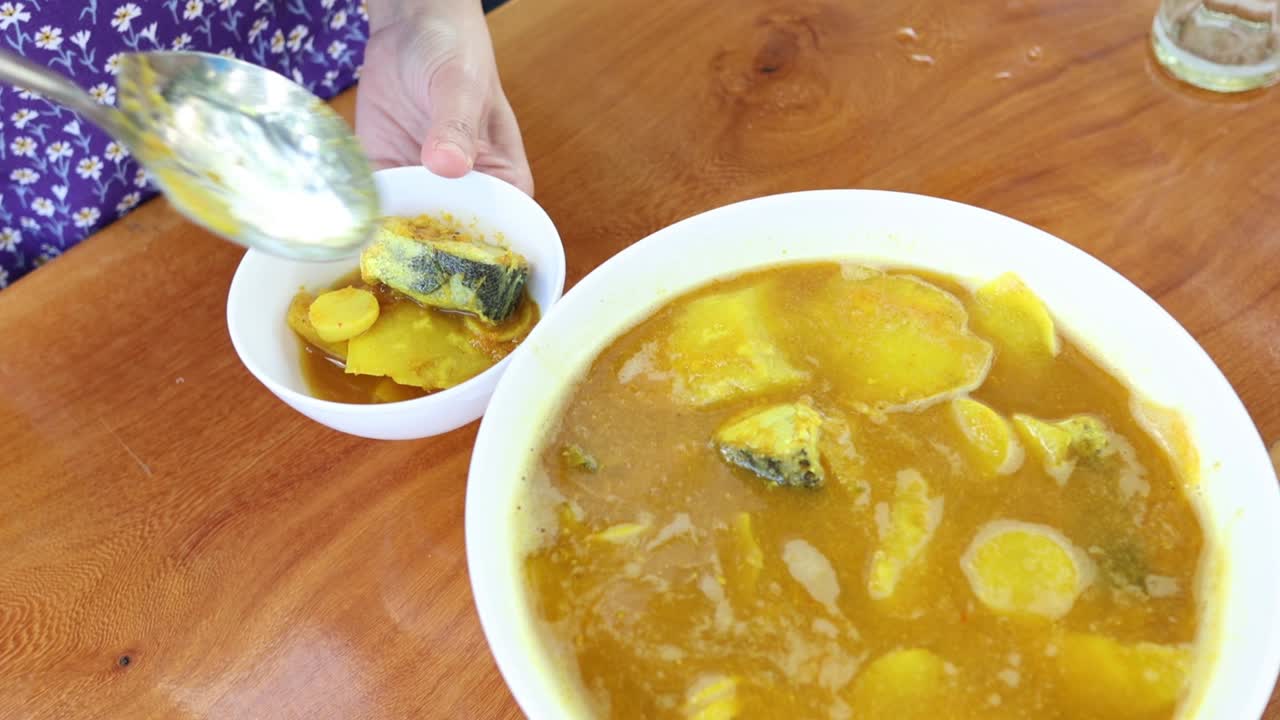 persona que sirve curry de pescado en varios cuencos