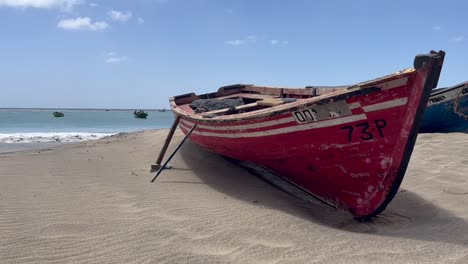 Red-fishing-row-boat-leaning-on-beach-in-Cape-Verde