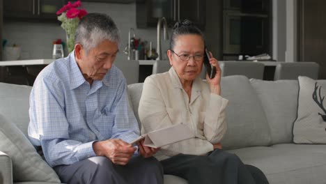 front view of old senior asian couple using multimedia device in a comfortable home 4k