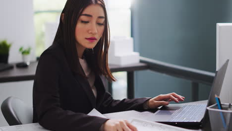 asian architect translating floor plan measurements on laptop