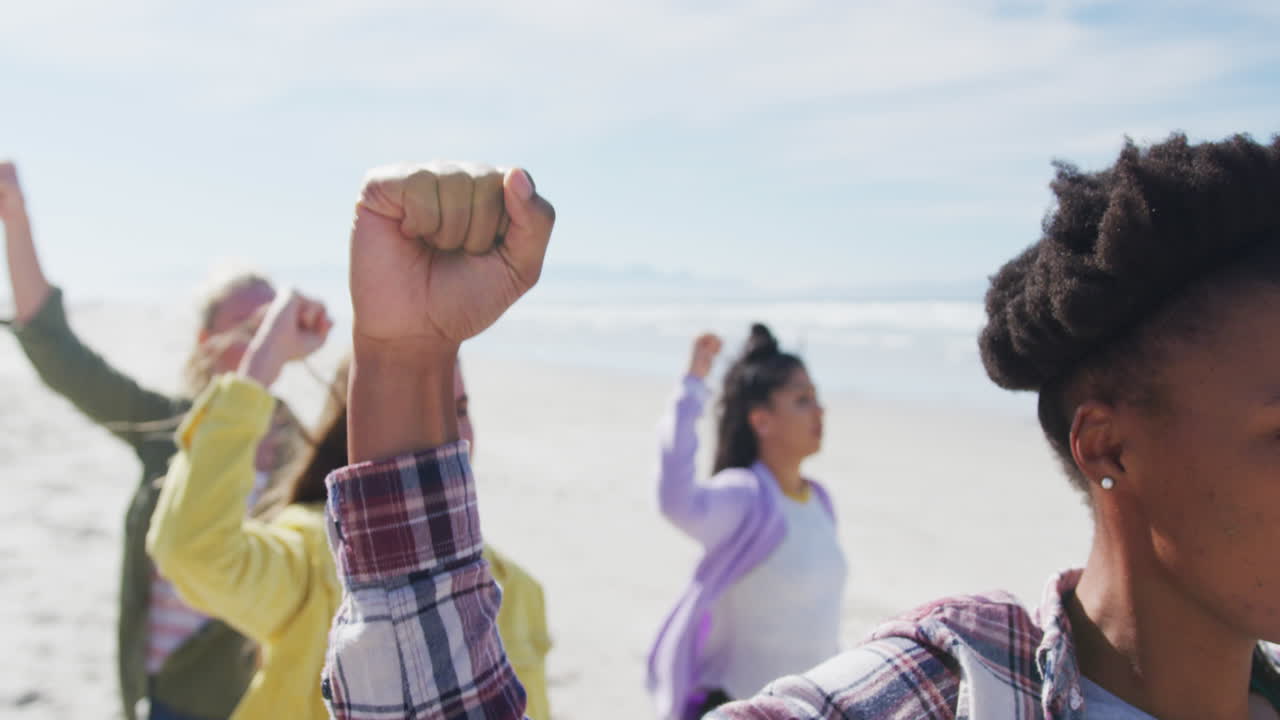grupo diverso de amigas levantando puños en la playa