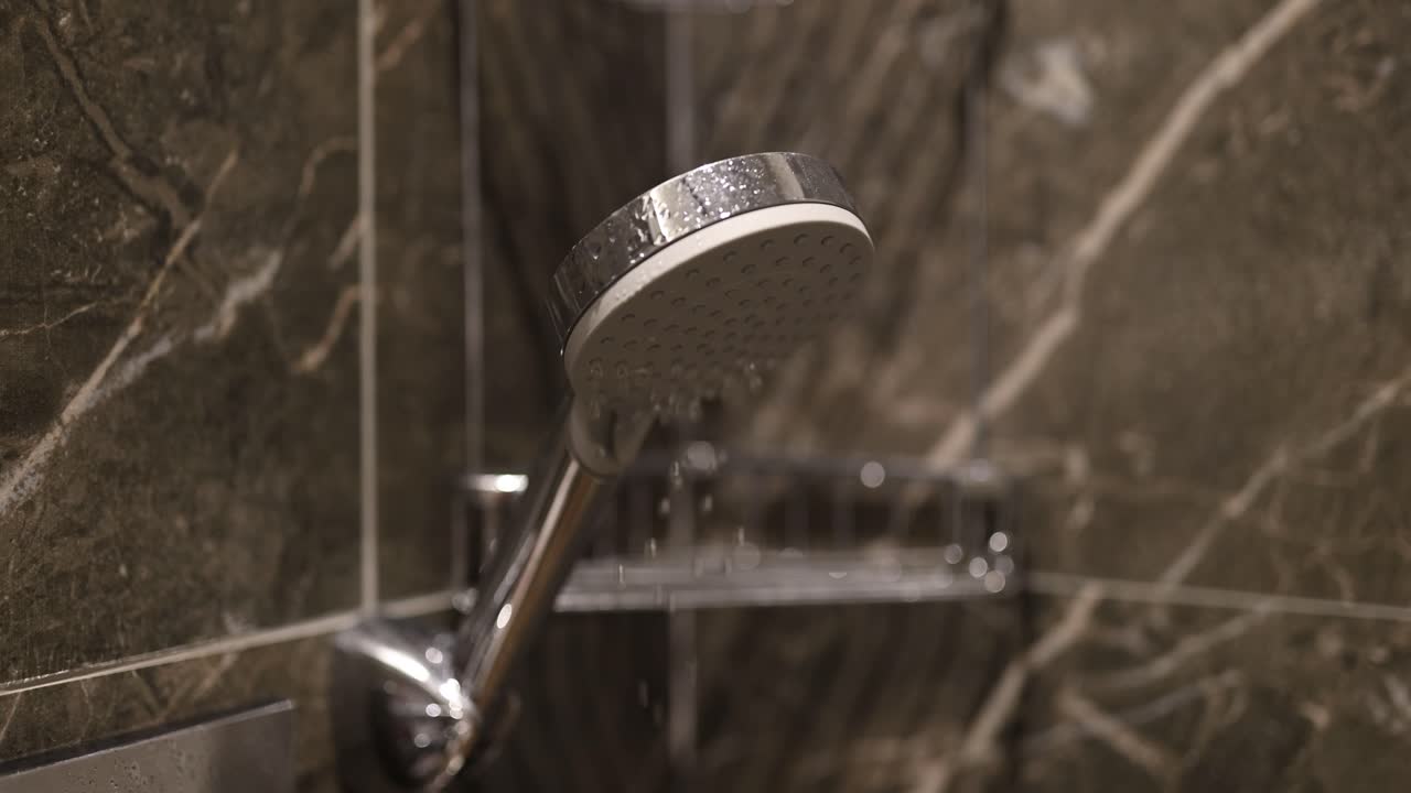Close-up of a Modern Shower Head with Water Drops in a Tiled Bathroom