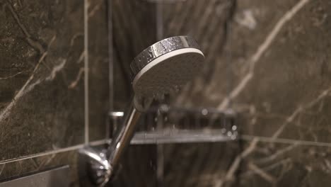close-up of a modern shower head with water drops in a tiled bathroom