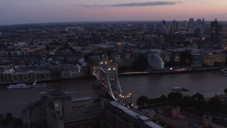 Luftaufnahme-Von-Booten,-Die-Auf-Der-Themse-An-Der-Tower-Bridge-Schwimmen.-Beleuchtete-Berühmte-Brücke-Am-Abend.-London,-Vereinigtes-Königreich