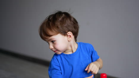 cute caucasian baby puts the ring from toy pyramid on his head. little kid pays happily at home.