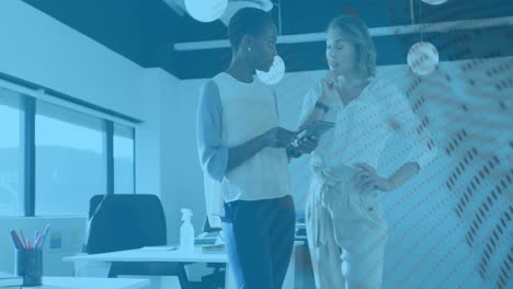 animation of graphs and globe over diverse female coworkers in office