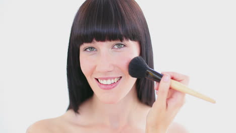 happy brunette woman using a powder brush