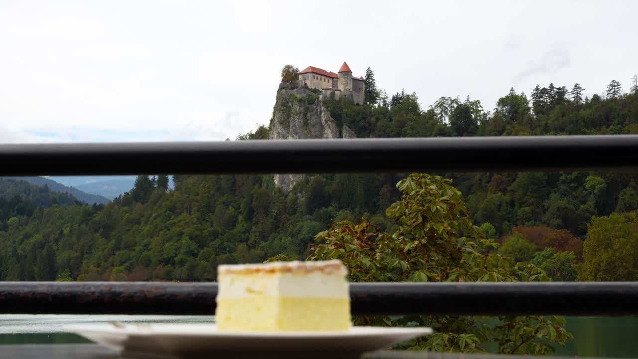 Il tradizionale dessert Kremsnita, torta alla crema di Bled, con strati di panna montata, servito in un caffè all'aperto con il castello sullo sfondo