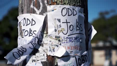 a close-up view of community job listings on a weathered telephone pole, showcasing various 'odd jobs' advertisements with flyers and contact information
