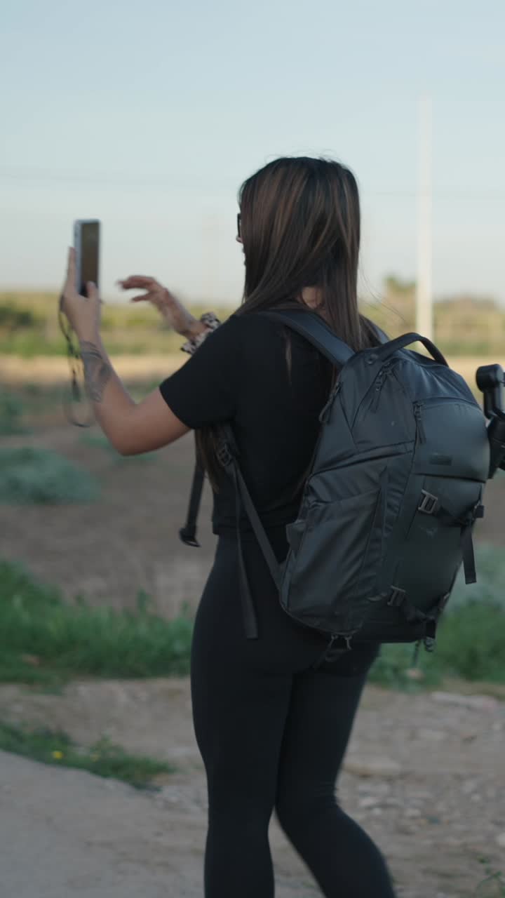 A woman taking pictures or selfies outdoors with her phone
