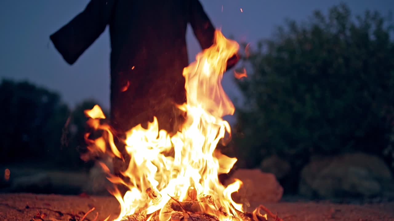 Fire on the ground and scary black silhouette. Horror atmosphere at flame at dark. Mysterious ghost near bonfire.