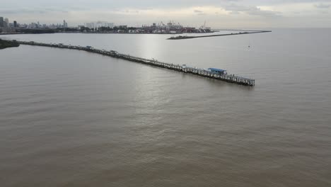 aerial view of pier extending from land out over water in the vast endless ocean