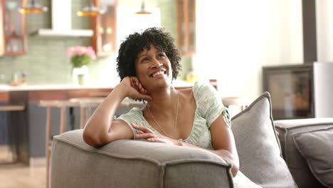 retrato de una feliz mujer afroamericana en el sofá en una sala de estar soleada, espacio de copia, cámara lenta