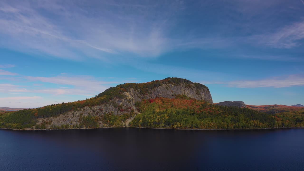 Plano aéreo deslizando para a direita, passando pela Montanha Kineo sobre o lago Moosehead no outono.