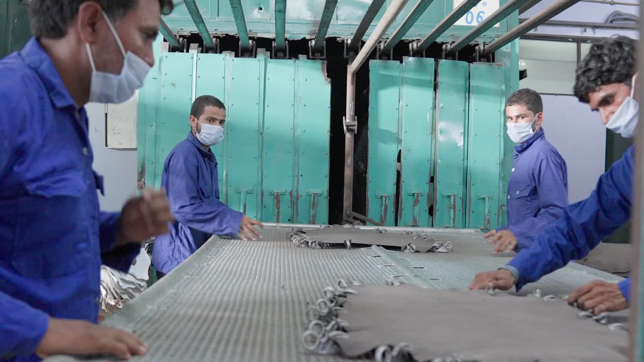 Production Line Workers Taking Clamps Of Tanned Animal Hides In A Industrial Leather Factory.
