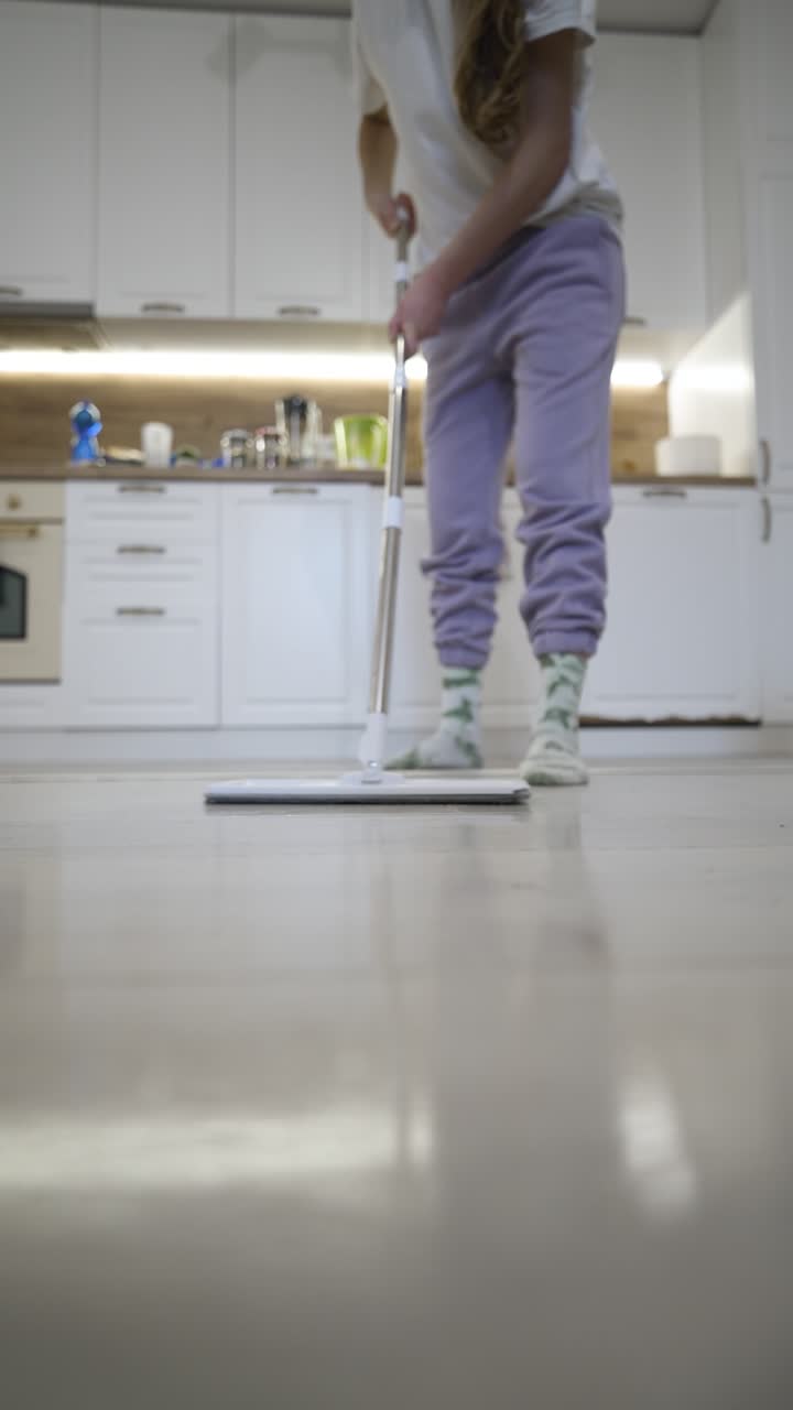 Vertikal video viser et nærbilde av et mopphode som beveger seg over gulvet, og fanger opp hjemmerengjøring, hygiene og daglig husholdningsvedlikehold under en rutinemessig innendørs syssel.