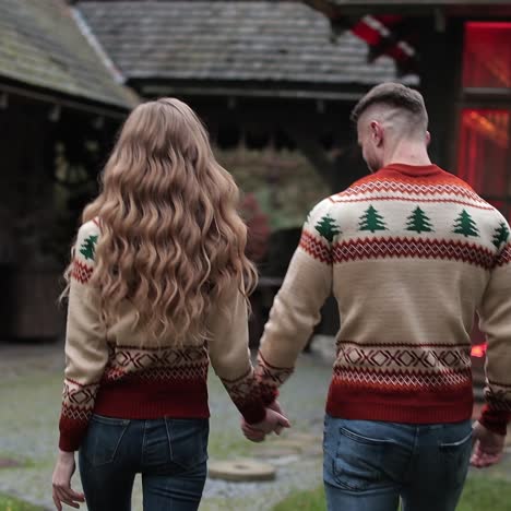 smiling couple coming closer to the country house. pair in similar clothes walking near the beautiful village manor