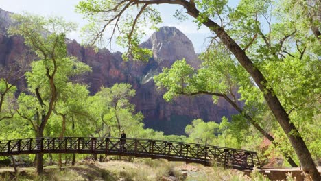 Ultra-slow-motion-shot-of-woman-walking-bridge-over-the-Virgin-River-in-Zion-National-Park,-Utah