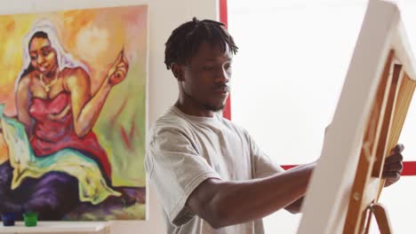 african american male painter painting on canvas in artist studio
