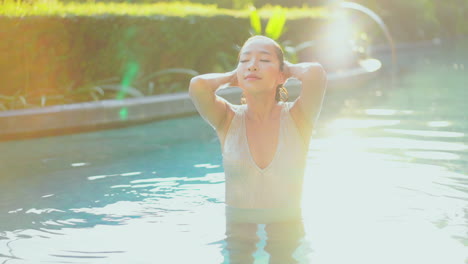 Pequeña-Mujer-Asiática-Sexy-En-La-Piscina-Con-Las-Manos-En-El-Pelo-Mojado-Mira-A-Cámara-Lenta-En-Un-Brillante-Día-De-Verano