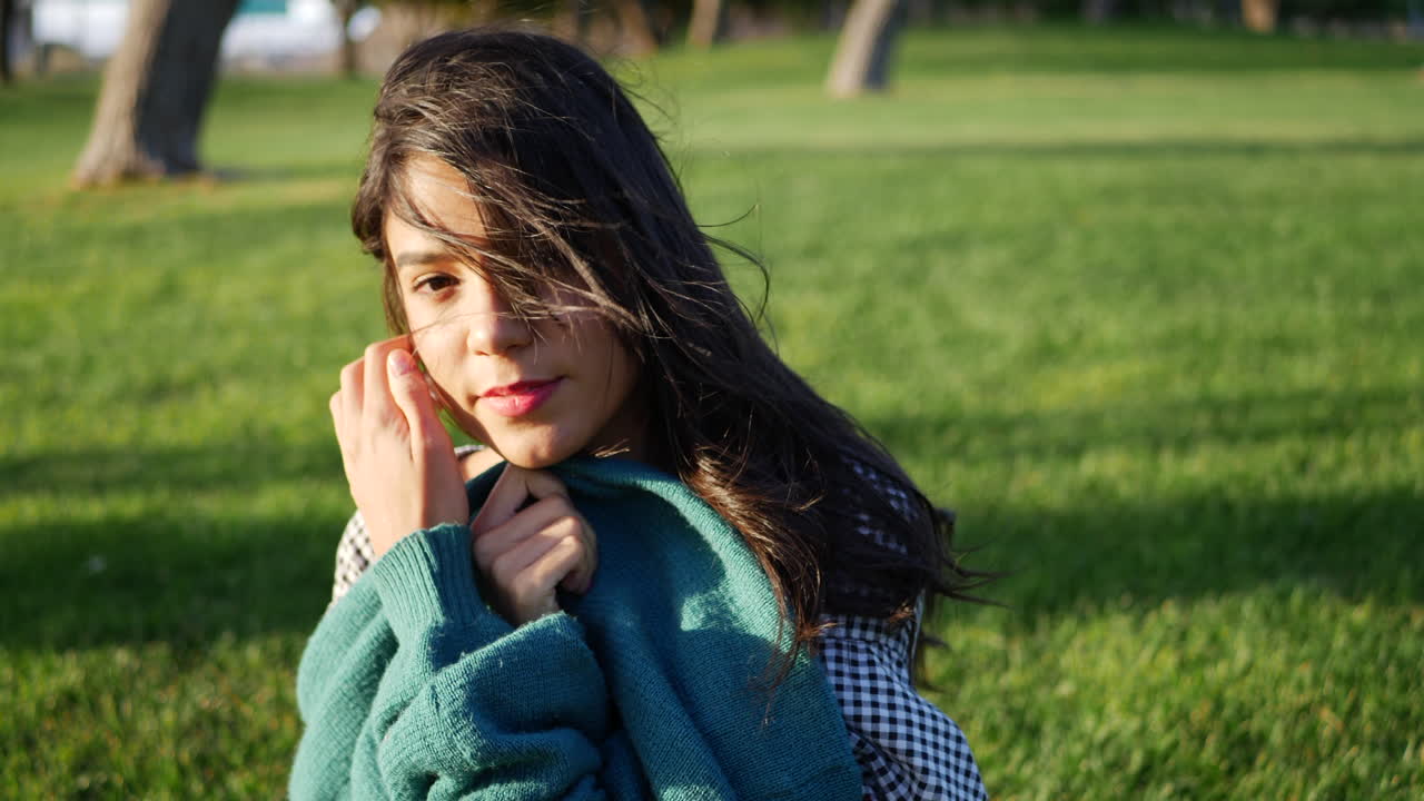 An attractive young hispanic woman trying to get warm and cozy with her sweater in cold windy weather