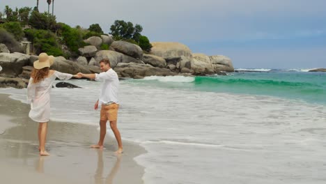 vista lateral de una pareja caucásica caminando de la mano en la playa 4k '