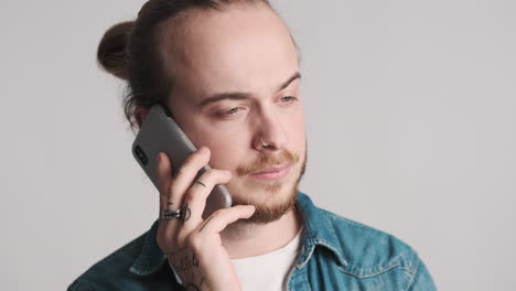 un joven caucásico hablando por teléfono.
