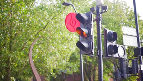 Green-light-turning-orange-and-red,-on-a-London-road-next-to-a-park