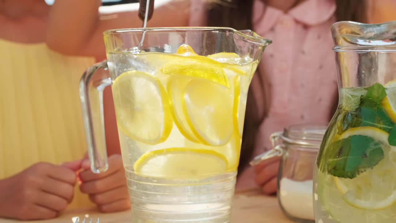 Hands Of Girls Stirring Lemonade With Spoon