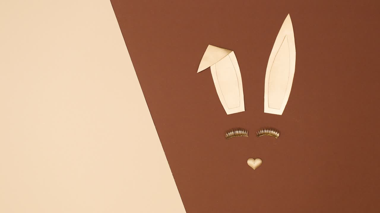 Making creative golden bunny with blinking eye lashes on nude brown background. Stop motion