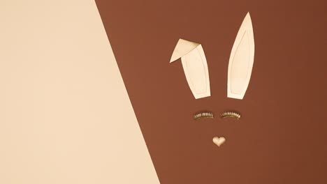making creative golden bunny with blinking eye lashes on nude brown background. stop motion