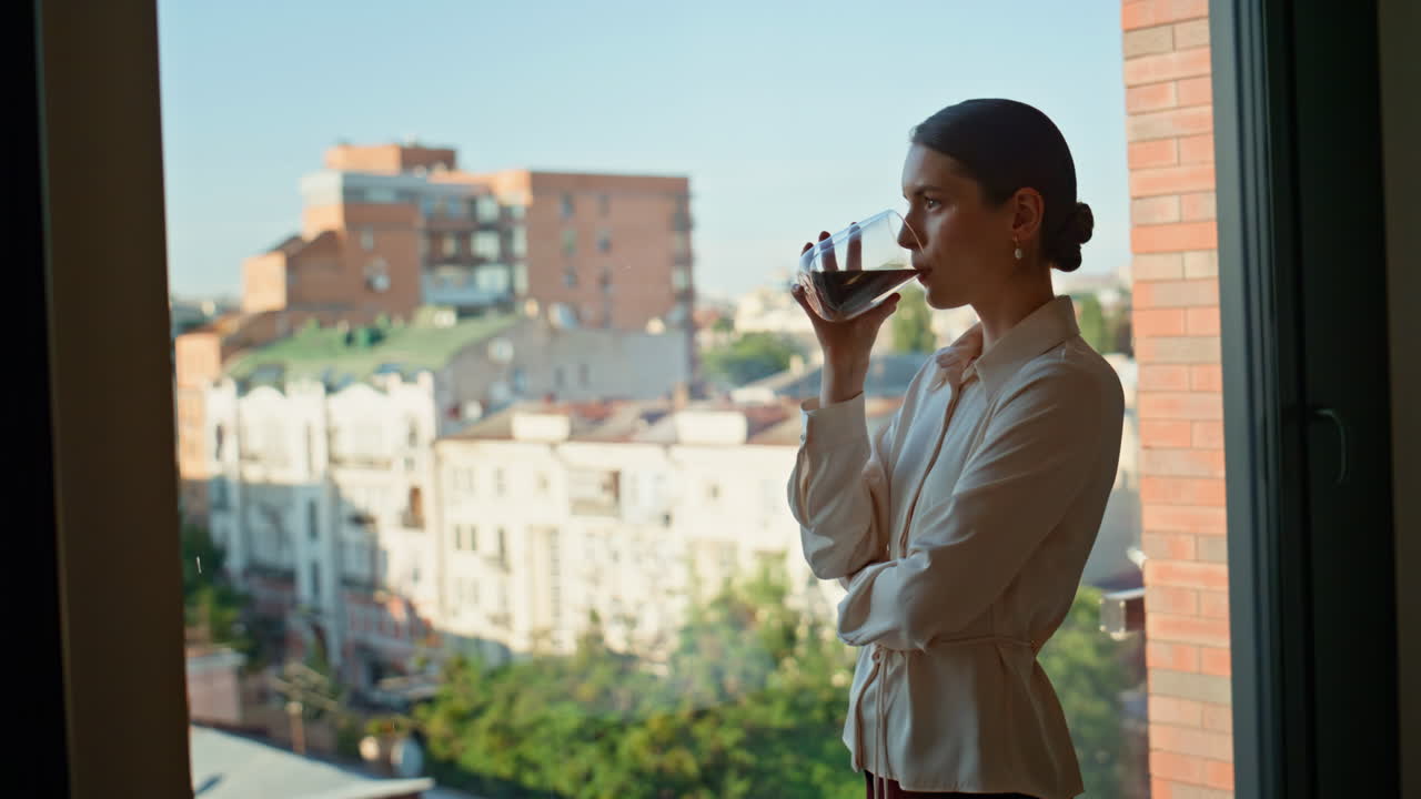 Primer plano de un ejecutivo sujetando una taza de café y disfrutando de las vistas urbanas desde la ventana