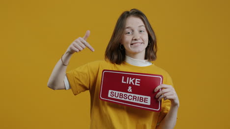 woman holding a "like & subscribe" sign