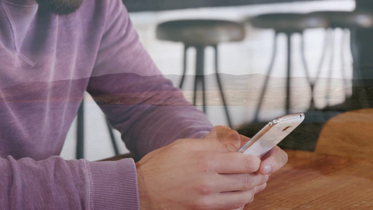 Cliente uomo che guarda in basso e sorride, scorrendo il telefono con i pollici e controllando i messaggi di lavoro.