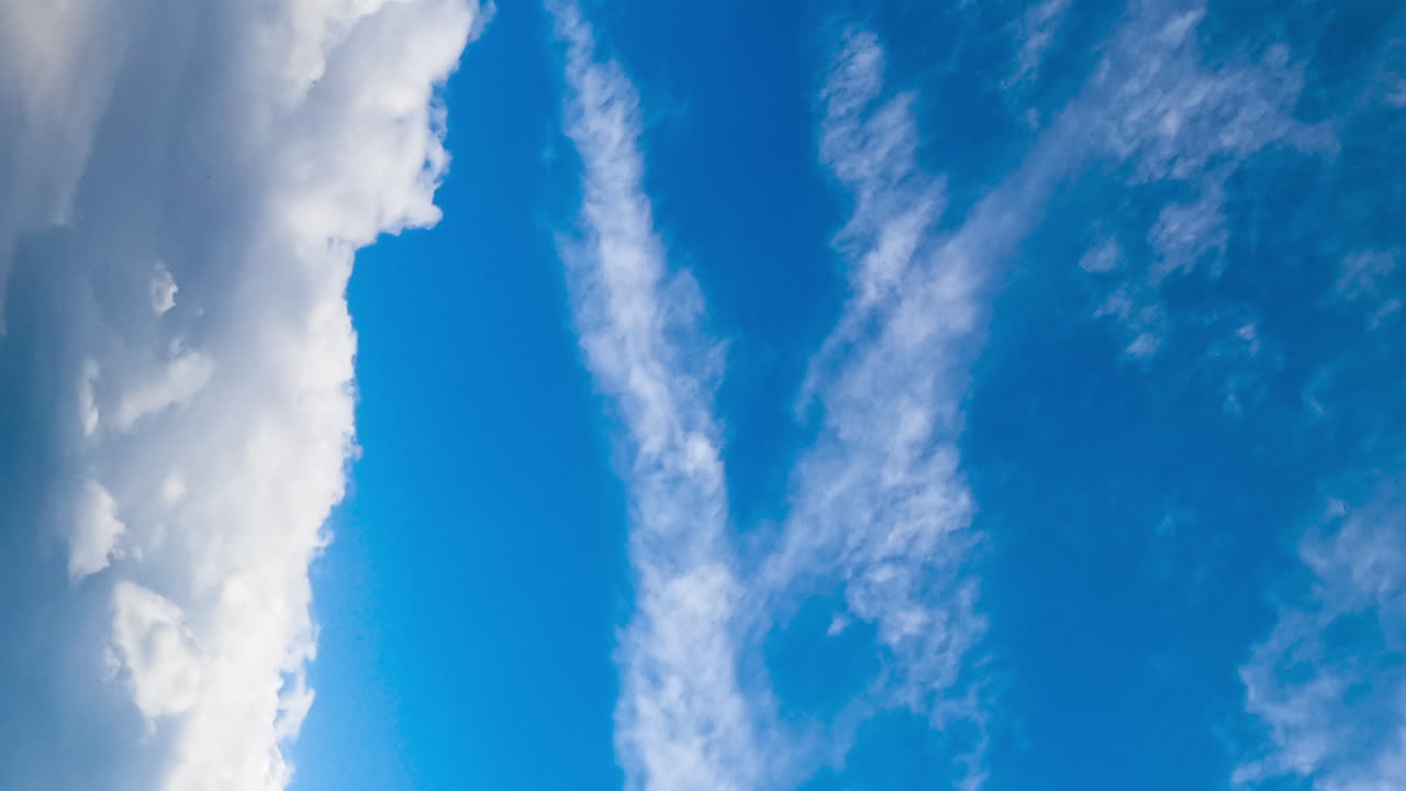 Blue sky with cumulus clouds moving quickly. Rainy cloudscape formation. Low angle view. Timelapse. Vertical screen.