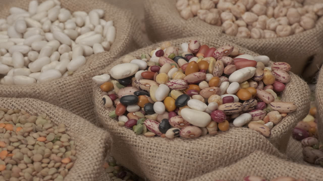 Mixed various legumes dry beans rotating on jute bowl. Typical vegan vegetarian ingredient, health Mediterranean diet food