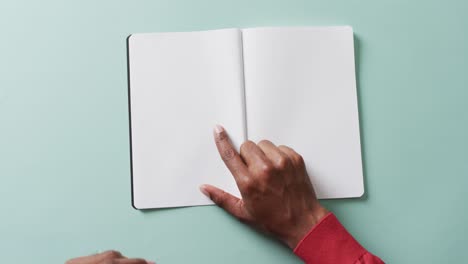 Close-up-of-hand-writing-with-pen-on-book-with-copy-space-on-white-background-in-slow-motion