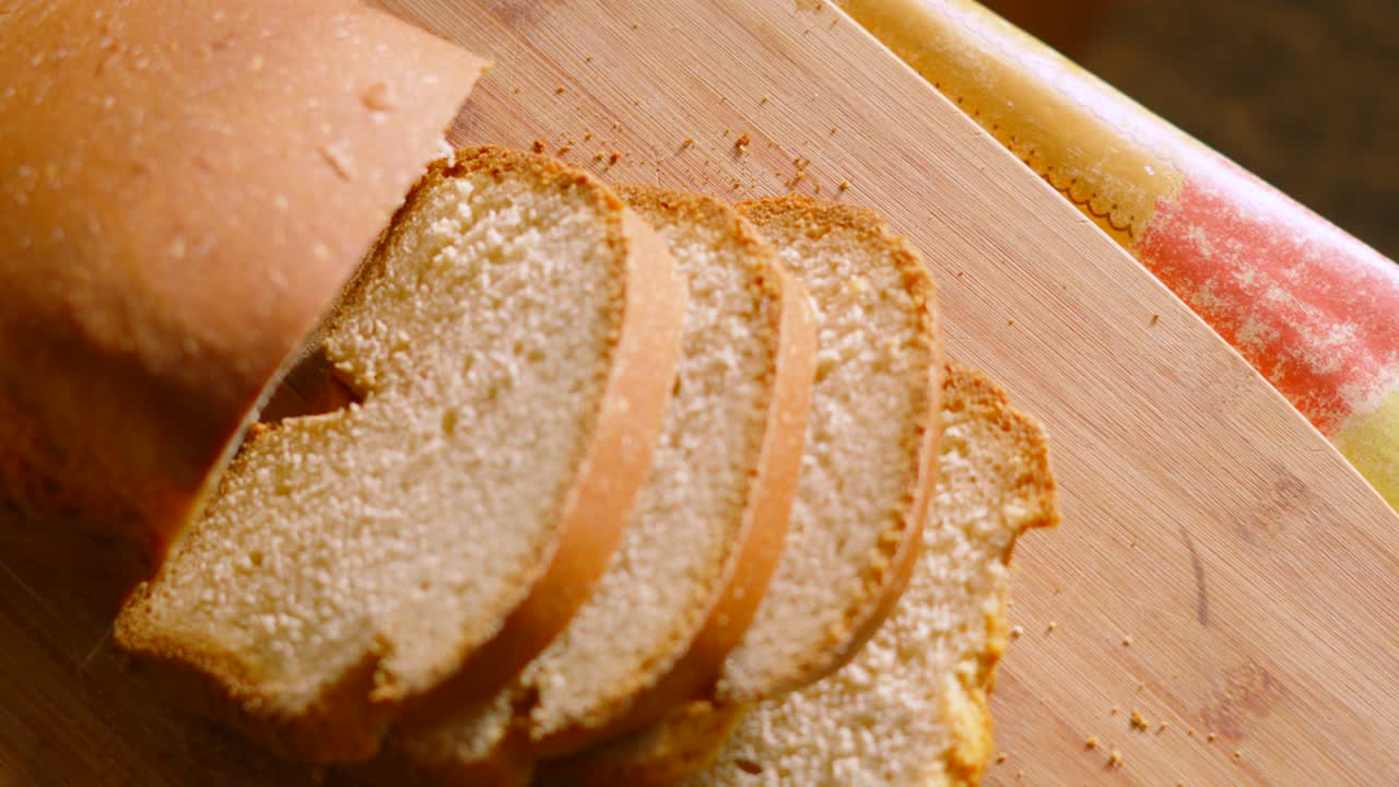 Overhead View of Freshly Baked Homemade White Bread with Slices on Wooden Chopping Board in Kitchen Setting with Crumbs. Home Baking Footage with Simple Healthy Ingredients 4K.