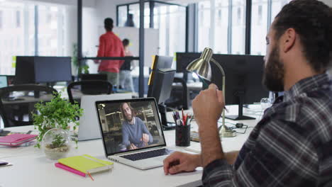 hombre de oriente medio teniendo una videollamada con un colega masculino en una computadora portátil en la oficina