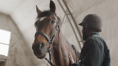 厩舎で馬をかわいがるジョッキー