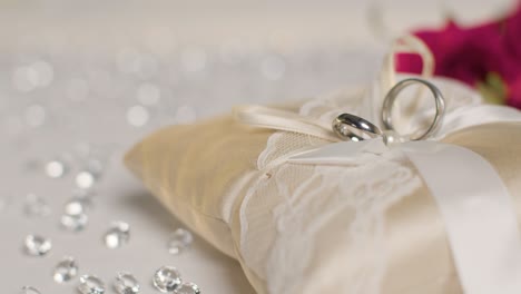 close up of wedding rings for bride and groom on small decorated cushion