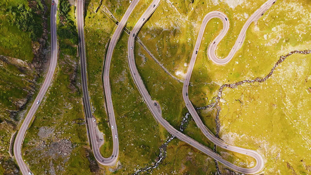 Winding road on the green mountain slope. Drone rising over the Carpathian Mountains and Transfagarash highway in Romania