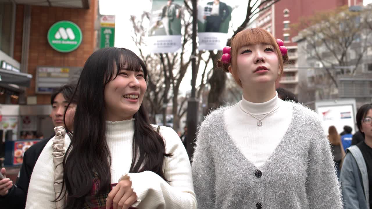 Hai người phụ nữ Nhật Bản sành điệu đi dạo qua Tokyo, chỉ vào các điểm tham quan dưới ánh sáng ban ngày rực rỡ