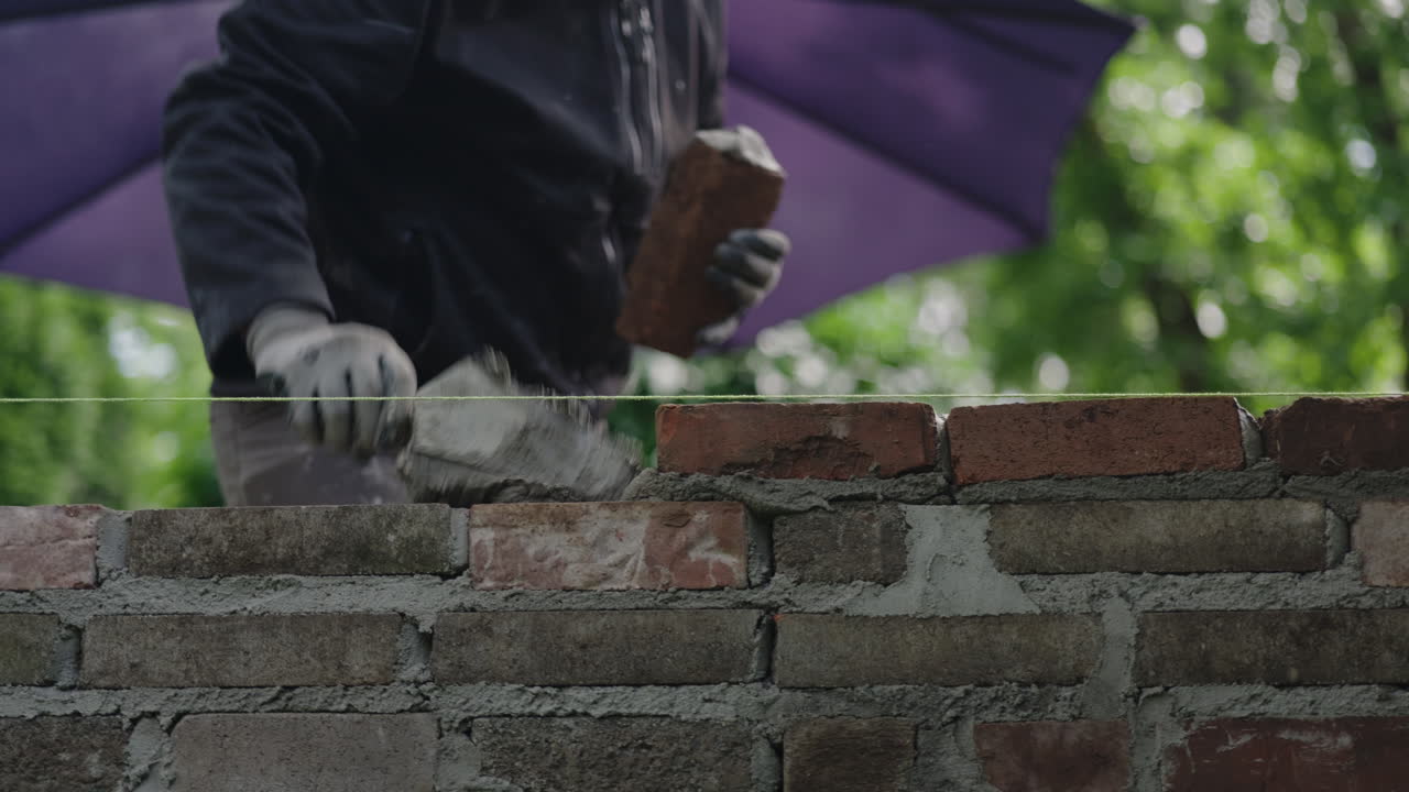 Masonry worker laying bricks outdoors in a backyard