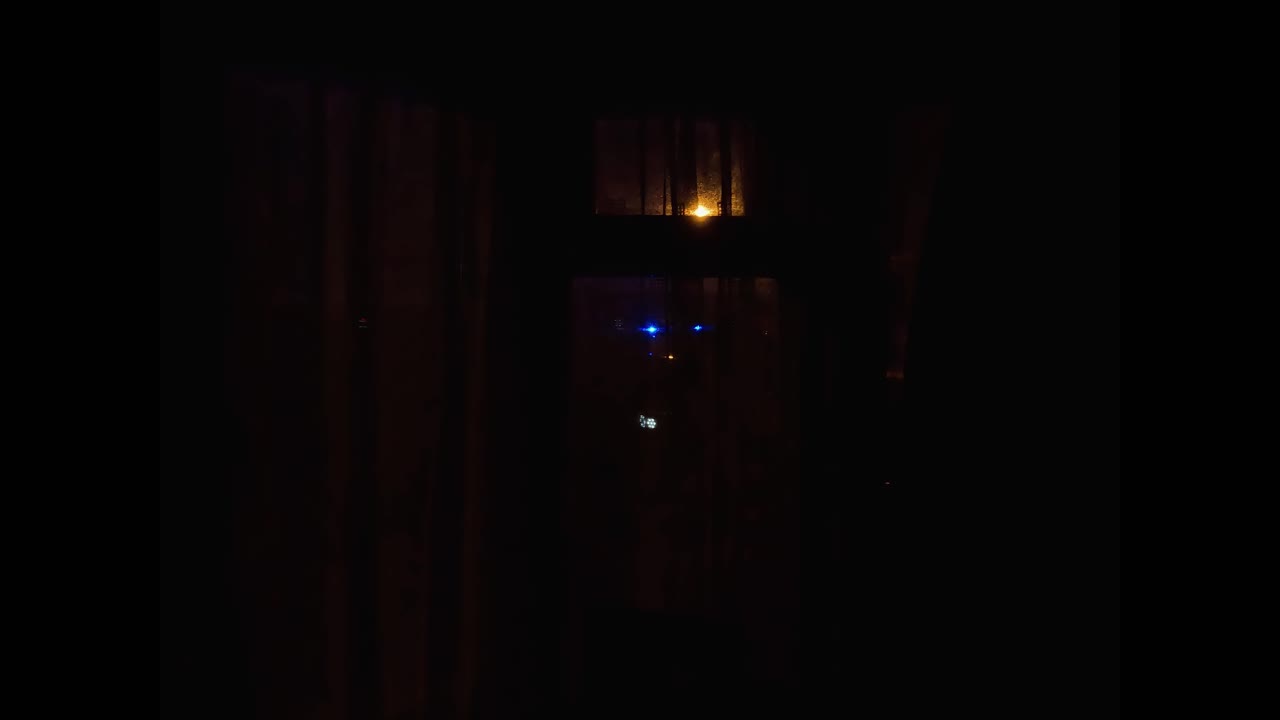 밤에 커튼을 통해 보이는 깜박이는 파란색 비상등